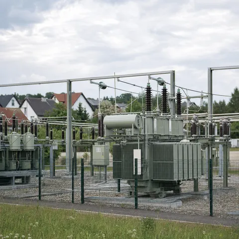 Illustration zum Abschnitt „Was Netzentgelte sind“ im Ratgeber „Netzentgelte: Warum Strom regional unterschiedlich viel kostet“: ein Umspannwerk mit Transformatoren im Stromnetz.