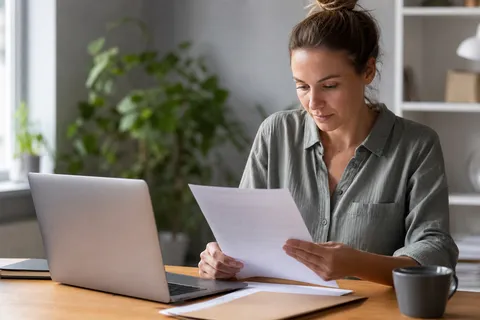 Symbolbild zum Ratgeber „Stromvertrag kündigen: Vorlage & Musterschreiben“: eine Person prüft am Laptop einen Stromvertrag am Schreibtisch.